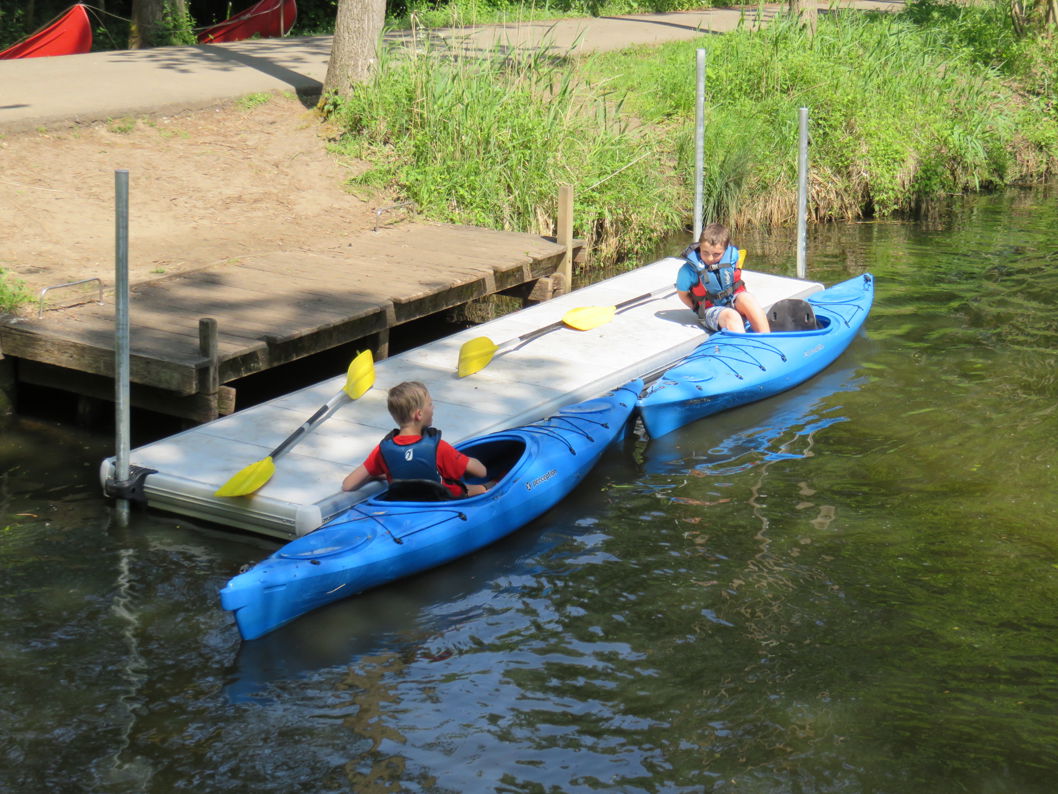 Kinderen zitten op een EasyFloat steiger en in een kajak met peddels, met gemakkelijke toegang tot het water in Puyenbroeck