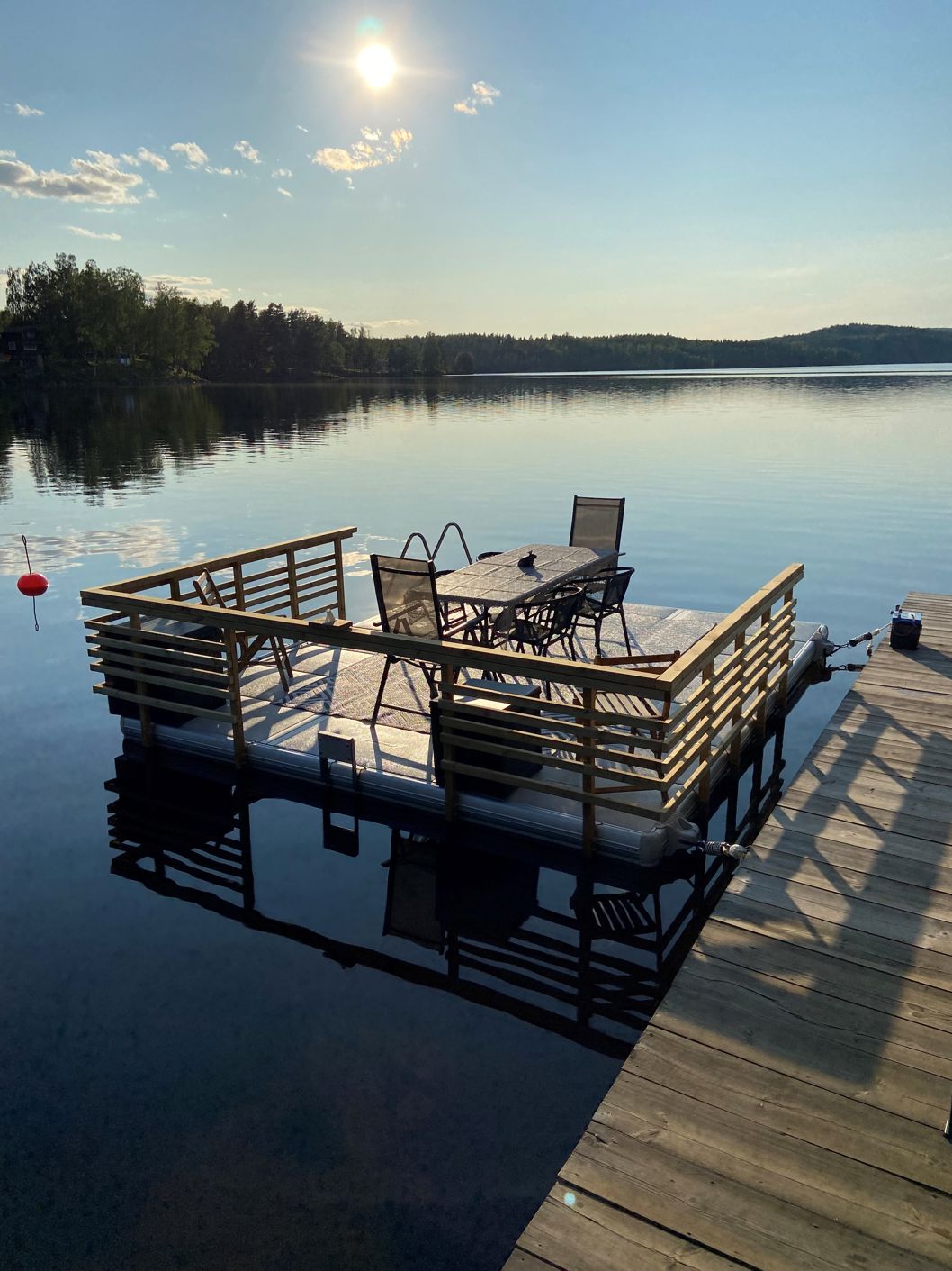 EasyFloat dock 3.6 × 4.2 m in Värmland with custom wooden railings, ladder, sun loungers, table, and motor mount on mirror-like water on a summer day
