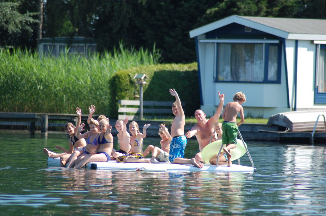 People enjoying an EasyFloat swimming raft on a lake in Holland, waving from the platform