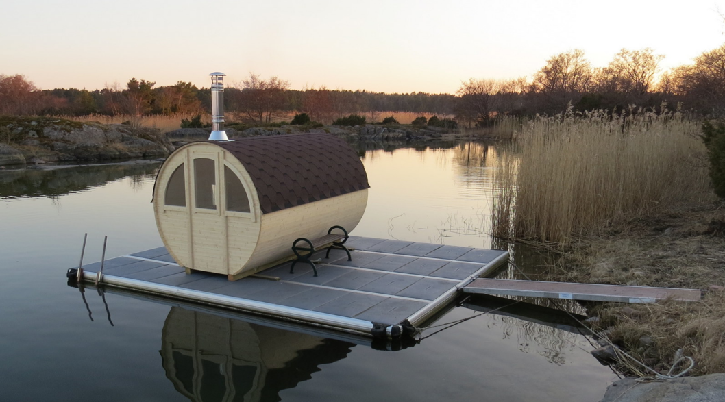 EasyFloat-Saunaflotte mit runder Sauna oben, Bank und Steg auf dem Wasser in herbstlicher oder frühlingshafter Umgebung.