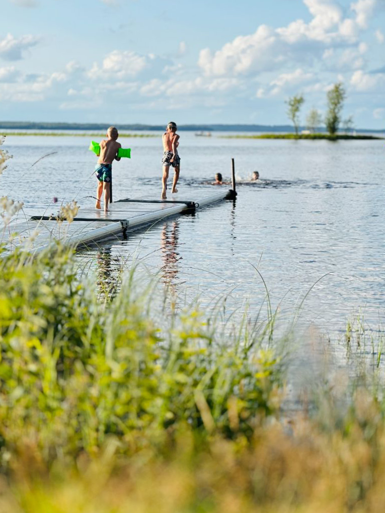 Barn som springer och hoppar på en EasyFloat badbrygga i Lagan under sommaren