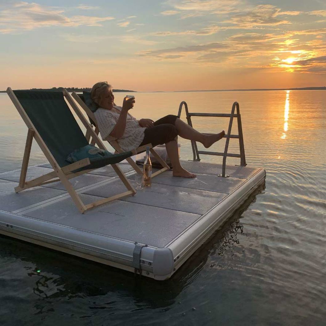 EasyFloat raft with swimming ladder and sun loungers on a lake at sunset