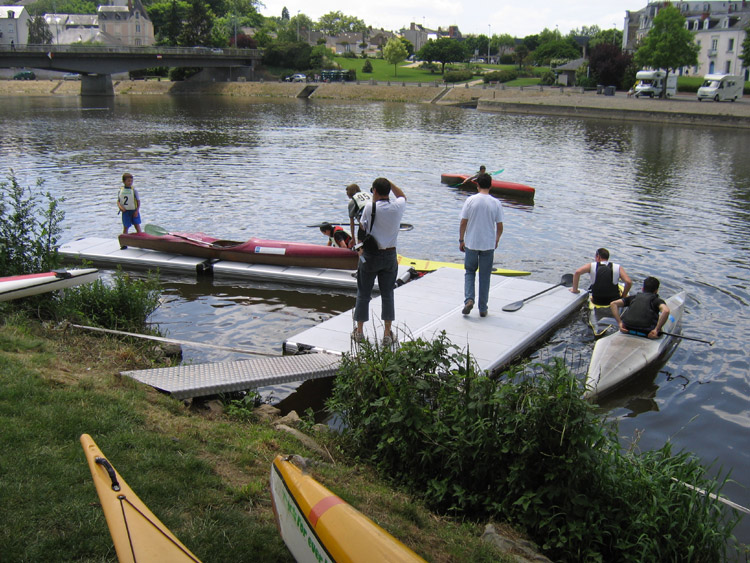 Kajaker vid och på EasyFloat bryggor i Château-Gontier, med människor på bryggorna och i båtarna