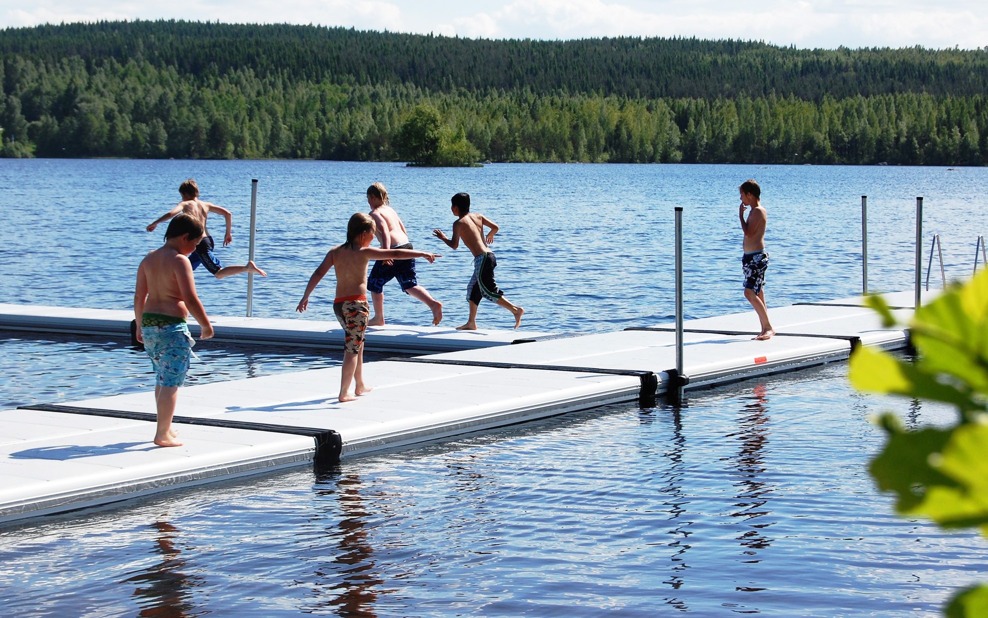 Offentlig badbrygga EasyFloat med badande människor vid en badplats.